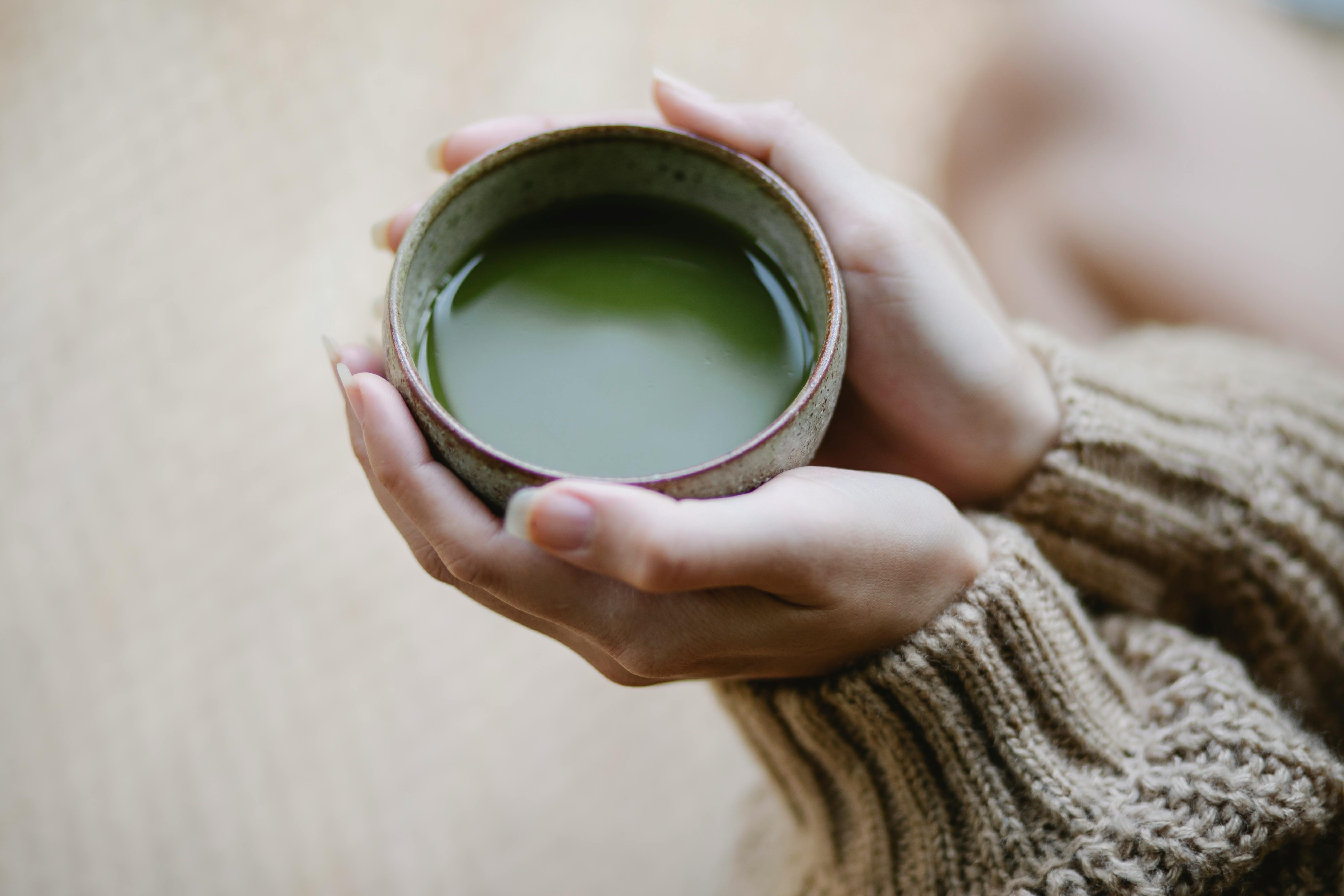 An image of green how matcha in a black bowl with syrup being poured over it.